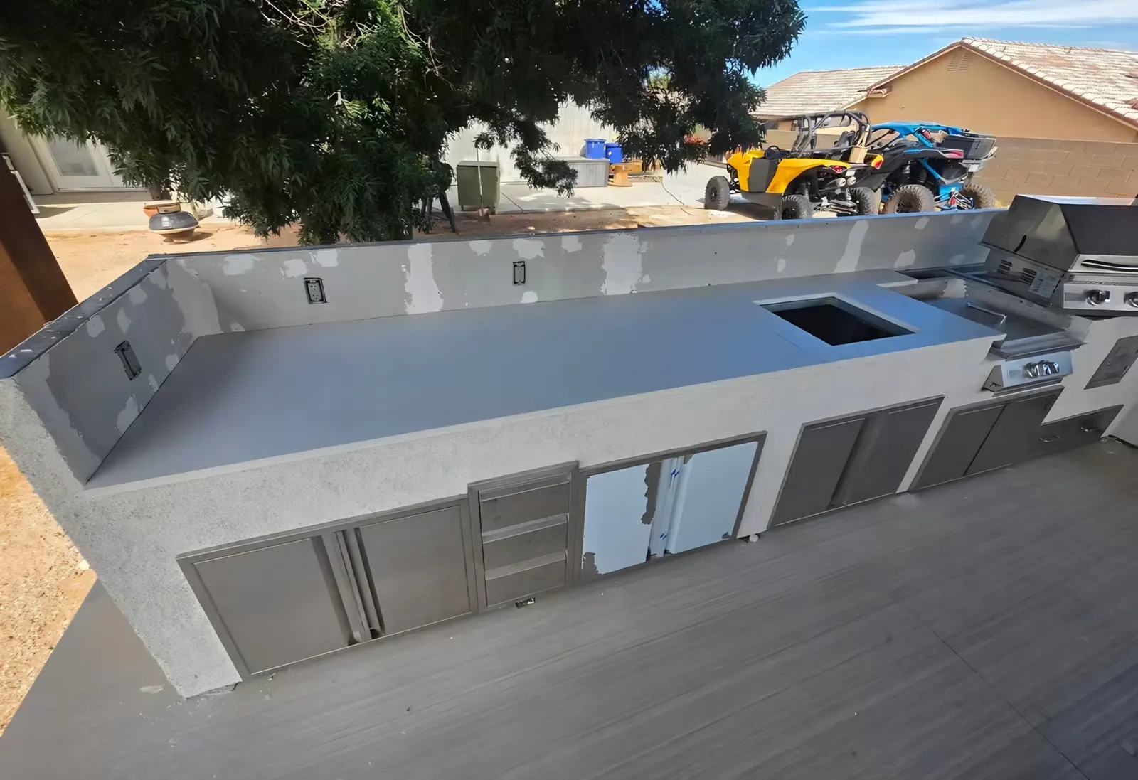 Long grey concrete countertop run on an outdoor kitchen island